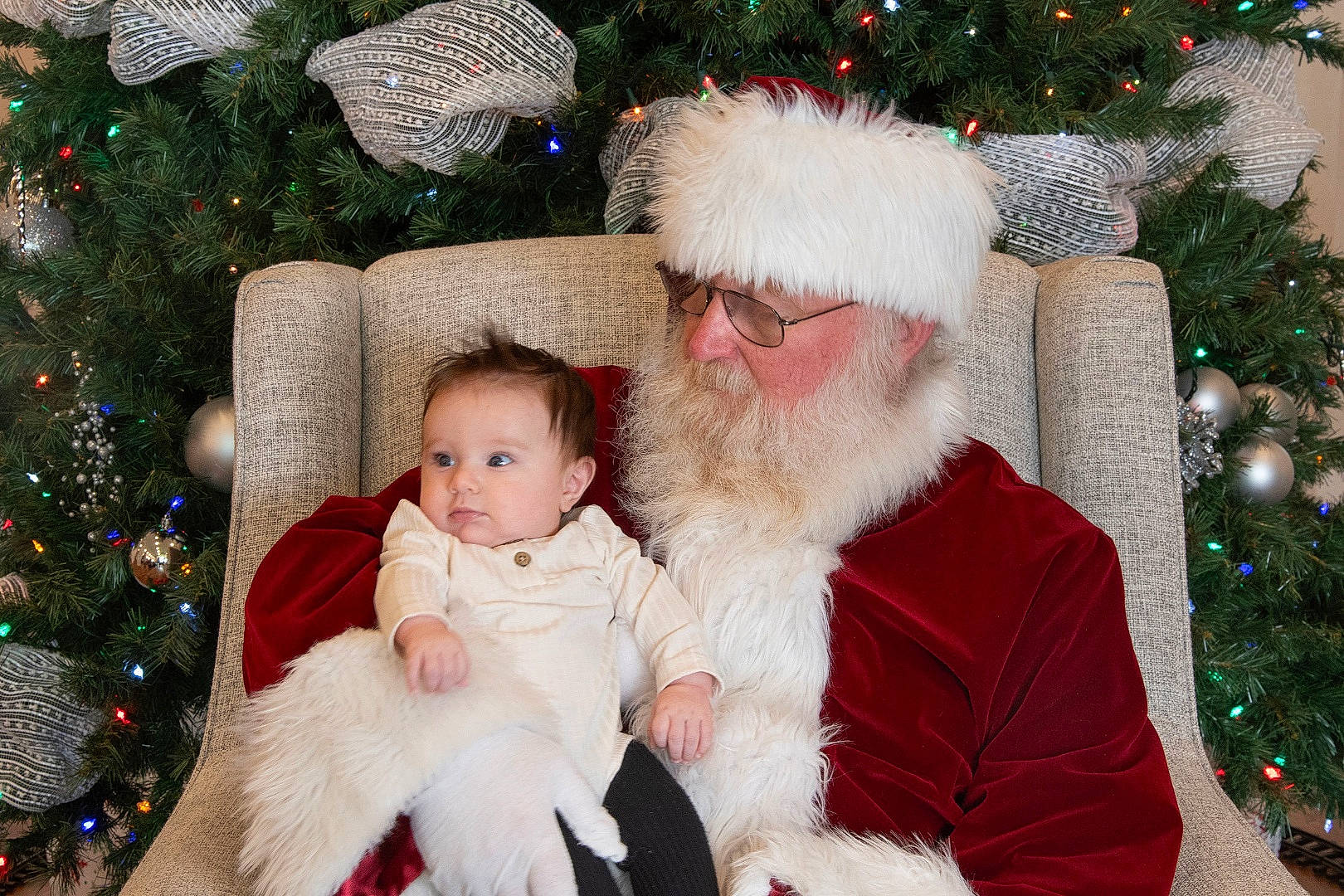 Penelope is registered to the contest to win money with this photo: beard, christmas_decoration, christmas_ornament, christmas_tree, face, fun, green, hair, happy, hat, head, headwear, holiday, human_body, lap, person, photograph, red, santa_claus, smile