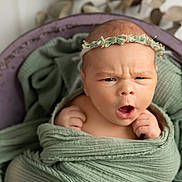 Iris a rejoint le concours — aidez-le/la à gagner de superbes lots ! baby, newborn, infant, wrapped, blanket, headband, flower_crown, green, portrait, cute, expression, face, hands, soft_texture, cozy, indoor, closeup, skin, child, adorable