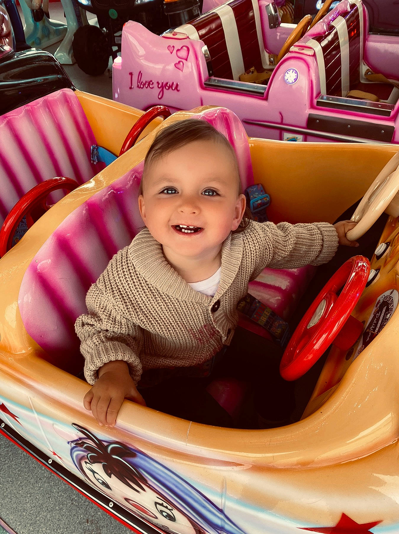 Athénaïs a rejoint le concours — aidez-le/la à gagner de superbes lots ! automotive_design, baby_toddler_clothing, chair, child, comfort, facial_expression, fun, happy, joy, leisure, magenta, motor_vehicle, person, pink, product, red, smile, tire, toddler, vehicle
