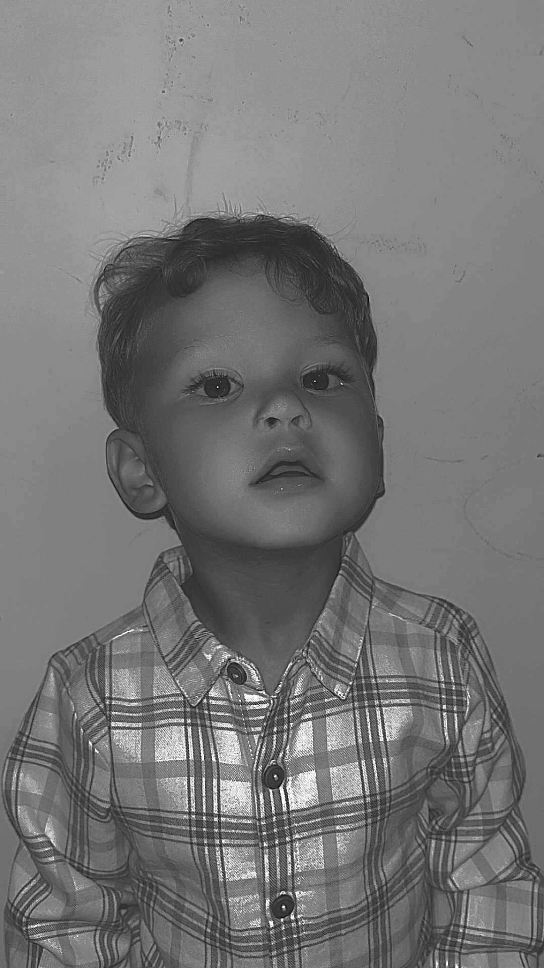 Lyann participe au concours pour gagner de l'argent avec cette photo : child, boy, portrait, curly_hair, plaid_shirt, buttoned_shirt, face, expression, indoor, young, curious, monochrome, black_and_white, casual_clothing, head_and_shoulders, looking_up, person, shirt, texture, wall