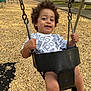 toddler, child, swing, playground, outdoor, smiling, curly_hair, wood_chips, trees, flowers, fence, chains, shoes, clothing, happy, person, park, daylight, adidas, seat