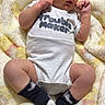 baby, infant, onesie, socks, blanket, soft_texture, clothing, cute, small_hands, small_feet, lying_down, indoors, newborn, portrait, child, person, sleepwear, cozy, resting, curious