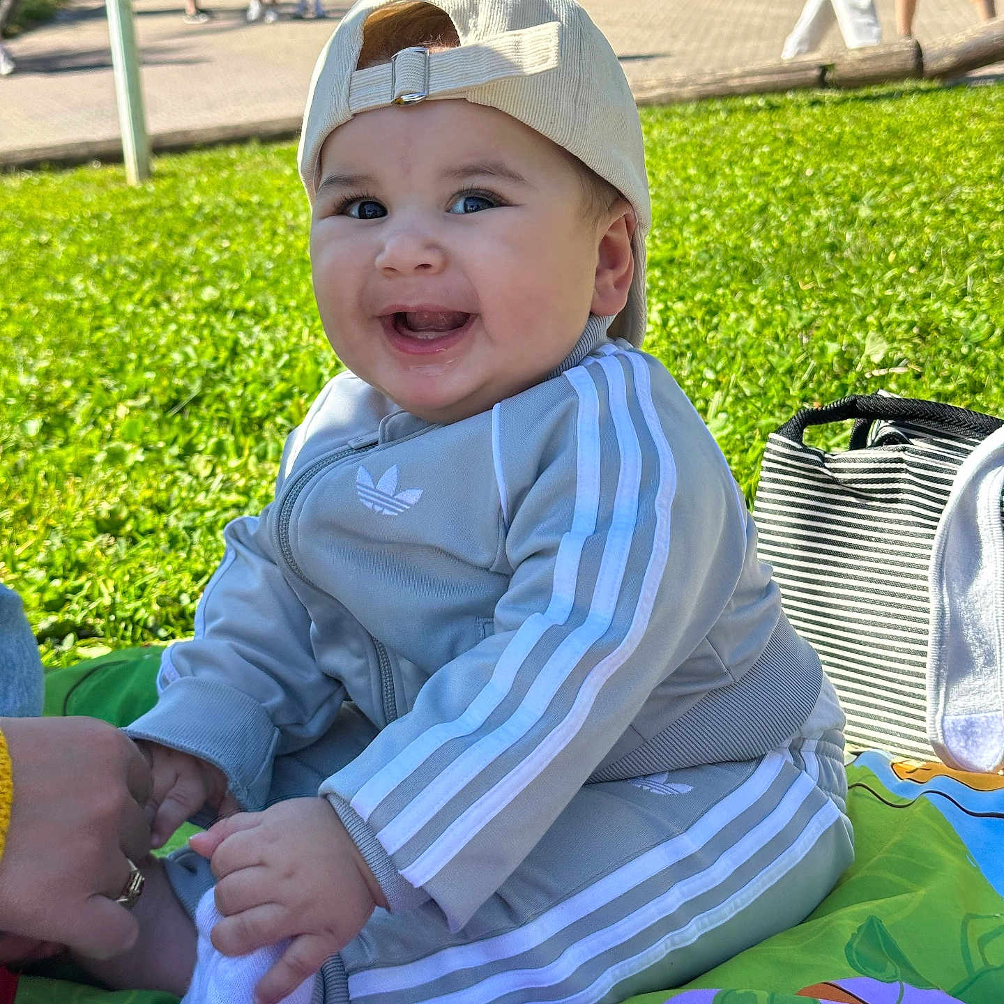 Zayn participe au concours pour gagner de l'argent avec cette photo : baby, child, smiling, outdoor, grass, cap, tracksuit, adidas, play_mat, hand, person, happy, sitting, toy, colorful, sunlight, park, casual_clothing, infant, cute