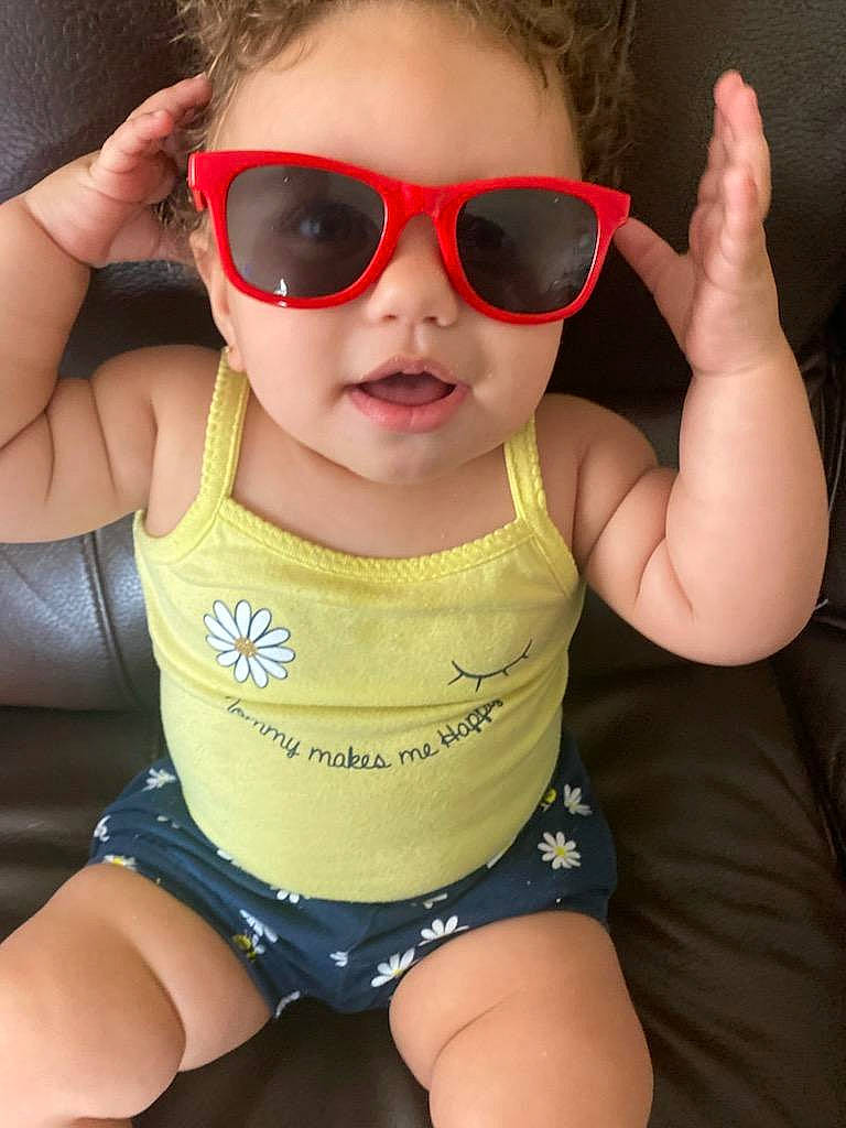 Melanie Jaye is registered to the contest to win money with this photo: arm, baby_toddler_clothing, cheek, eyewear, facial_expression, gesture, glasses, goggles, head, human_body, joint, lip, mouth, neck, organ, person, skin, standing, sunglasses, thigh