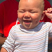 Elianna is registered to the contest to win money with this photo: baby, child, closeup, cute, dimples, expression, face, hand, happy, infant, joyful, outdoor, people, person, portrait, red_shirt, skin, smiling, striped_shirt, sunlight