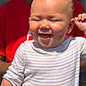 baby, smiling, dimples, striped_shirt, child, person, red_shirt, sunlight, happy, closeup, face, skin, hand, joyful, expression, portrait, outdoor, infant, cute, people