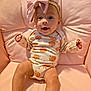 baby, child, infant, pink_bow, pumpkin_pattern, onesie, cushion, pink, smiling, happy, cute, sitting, face, headband, indoors, soft, plush, apparel, portrait, young