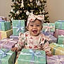 baby, child, smiling, christmas_tree, presents, gift_boxes, holiday, festive, ribbon, bow, headband, indoors, celebration, happy, cute, sitting, decorations, winter, holiday_lighting, joyful