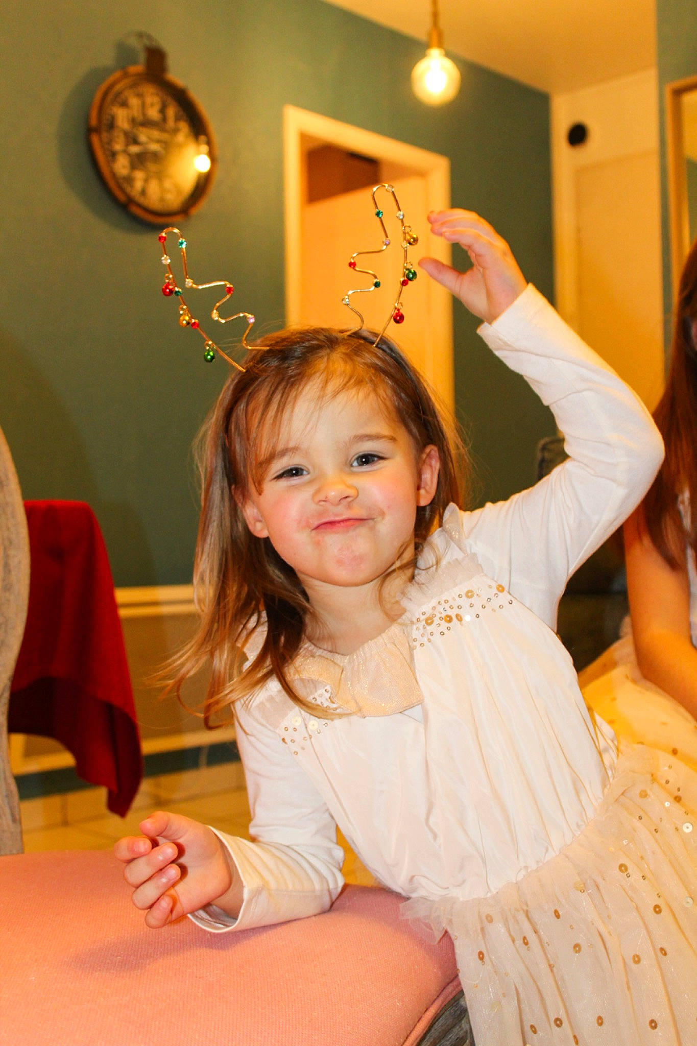 Amandine participe au concours pour gagner de l'argent avec cette photo : chair, child, clock, event, fashion_accessory, fun, hairstyle, happy, headpiece, human, joy, lighting, long_hair, peach, person, picture_frame, room, sitting, smile, table