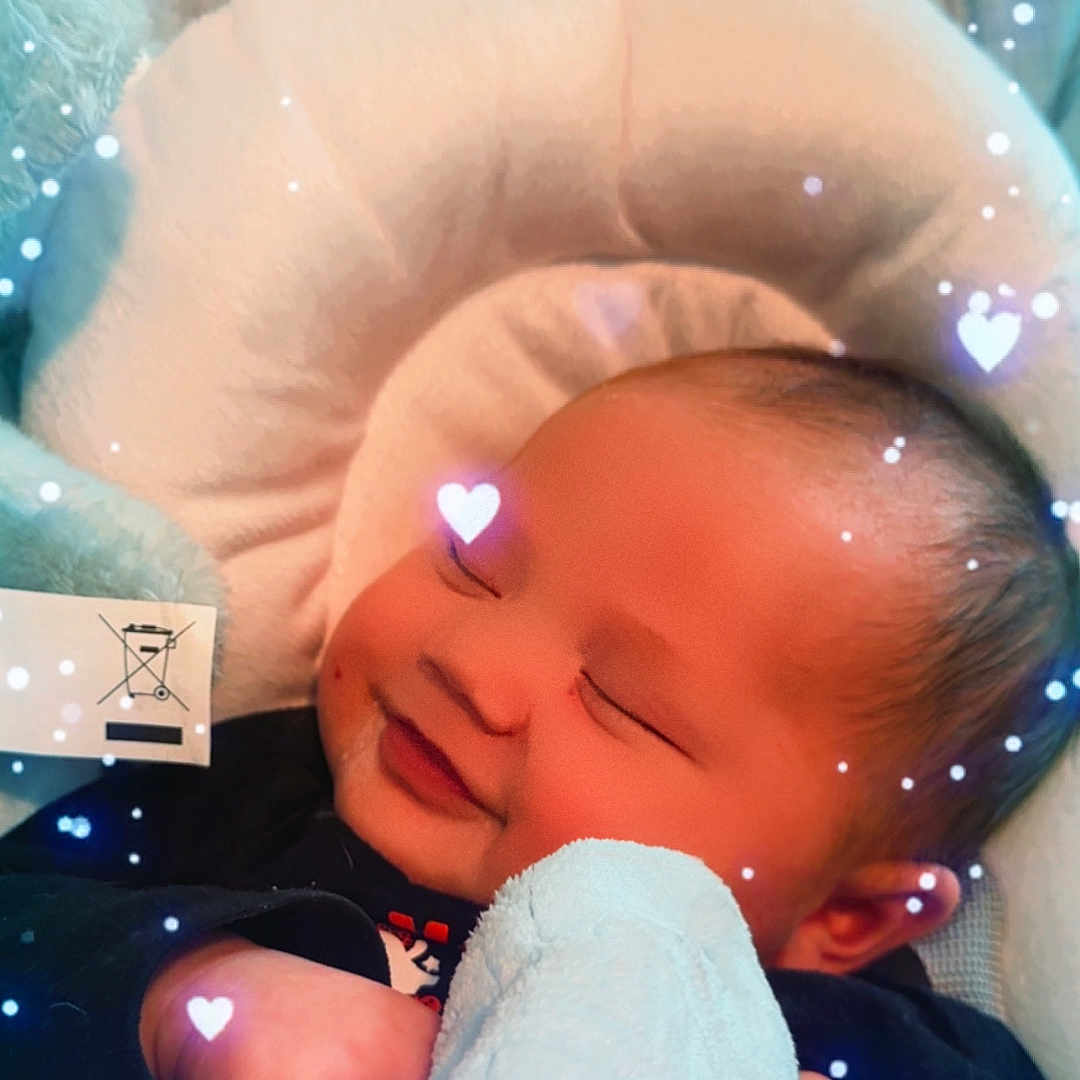Draycyn is registered to the contest to win money with this photo: adorable, baby, blanket, child, closeup, comfort, cozy, cute, face, head, heart_overlay, indoors, infant, pajamas, peaceful, resting, sleeping, smiling, soft_lighting, warm