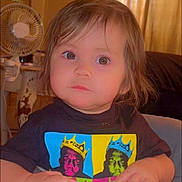Aubrey joined the competition — help win amazing prizes! toddler, child, portrait, face, curious, indoor, fan, clothing, graphic_tshirt, colorful, person, young_child, brown_eyes, short_hair, sitting, home, furniture, casual, expression, cute