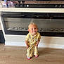 toddler, child, yellow_outfit, smiling, standing, wooden_floor, fireplace, modern_interior, tv, soundbar, red_bull_can, reflection, indoor, cute, happy, mismatched_slippers, home, person, blonde_hair, casual
