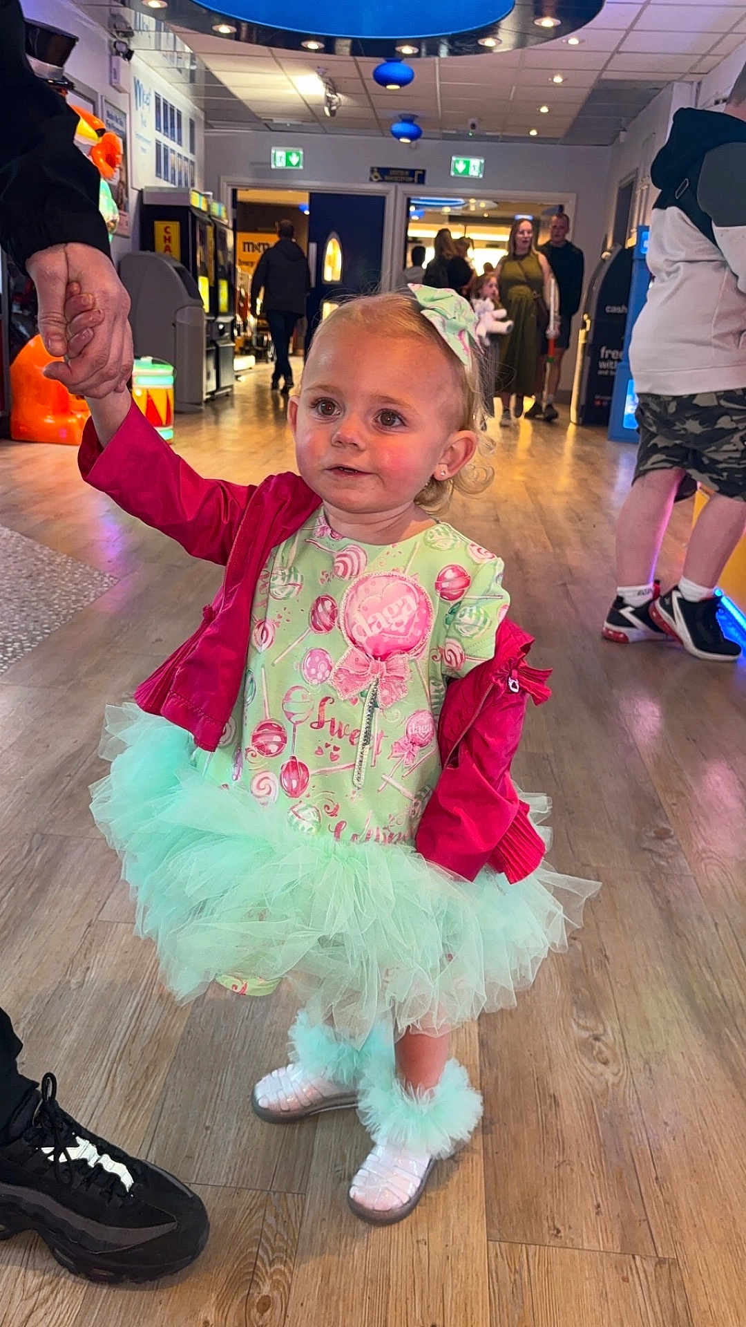 Dayla-Marie joined the competition — help win amazing prizes! toddler, child, indoor, arcade, floor, holding_hands, dress, tutu, boots, jacket, person, people, light, background, hand, hair_bow, smiling, walking, casual_clothing, public_space