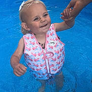 Dayla-Marie joined the competition — help win amazing prizes! toddler, child, pool, water, life_vest, swimming, smile, hand_holding, outdoor, playground, blue, pink, bow, happy, summer, fun, person, cute, skin, face
