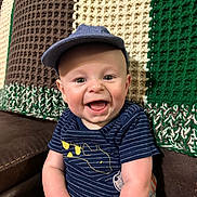 Kenton joined the competition — help win amazing prizes! baby, child, smiling, hat, blue_clothing, striped, couch, knitted_blanket, happy, sitting, indoors, cute, infant, portrait, face, cheerful, young_child, cap, clothing, person
