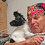 man, dog, pet, indoor, bandana, black_and_white, curious, holding, expression, casual, furniture, cardboard_box, sitting, portrait, animal, person, face, fur, human, closeup