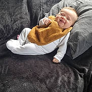 Nina participe au concours pour gagner de l'argent avec cette photo : baby, smiling, infant, couch, pillow, blanket, white_clothing, bib, happy, indoor, relaxed, face, child, young, cute, plush, soft, casual, comfort, resting