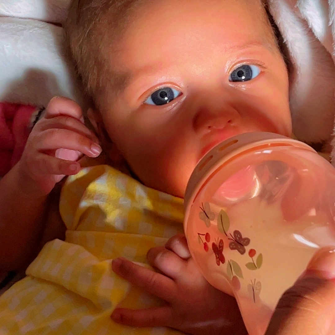Avaia is registered to the contest to win money with this photo: baby, blanket, bottle, butterfly, closeup, comfort, cute, eyes, face, feeding, hand, holding, indoors, infant, milk, newborn, person, skin, soft_light, yellow_clothing
