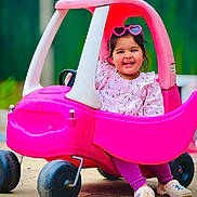 Sahibjot joined the competition — help win amazing prizes! child, toddler, toy_car, pink, sunglasses, heart_shaped, smiling, outdoor, play, happy, cute, clothing, footwear, plastic, wheels, portrait, daylight, fun, vehicle, person