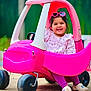 child, toddler, toy_car, pink, sunglasses, heart_shaped, smiling, outdoor, play, happy, cute, clothing, footwear, plastic, wheels, portrait, daylight, fun, vehicle, person