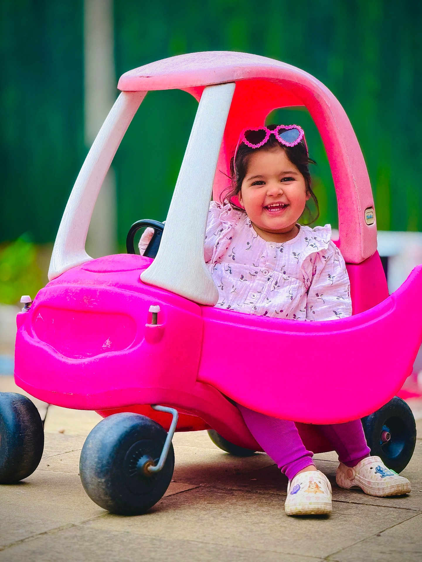 Sahibjot joined the competition — help win amazing prizes! child, toddler, toy_car, pink, sunglasses, heart_shaped, smiling, outdoor, play, happy, cute, clothing, footwear, plastic, wheels, portrait, daylight, fun, vehicle, person