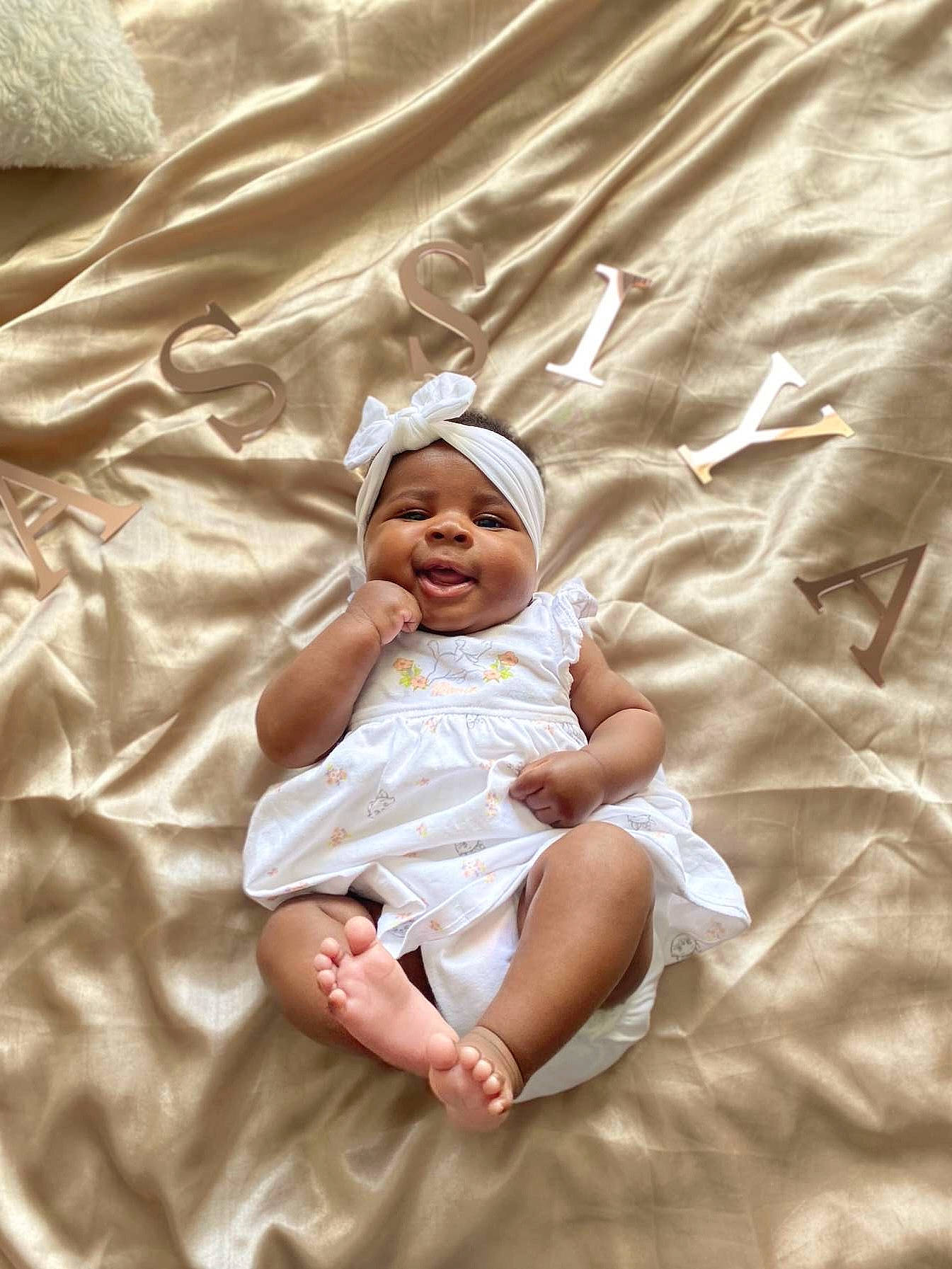 Assiya a rejoint le concours — aidez-le/la à gagner de superbes lots ! baby, baby_toddler_clothing, child, comfort, event, fun, grass, happy, headwear, linens, pattern, peach, person, portrait_photography, sand, sitting, skin, sleeve, smile, textile