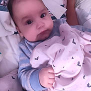 Michael is registered to the contest to win money with this photo: baby, blanket, bedding, plush_toy, infant, sleepwear, hand, face, lying_down, cozy, soft_toy, comfort, bed, child, cute, pattern, pink, blue, indoor, portrait