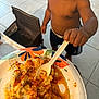 toddler, child, food, plate, spoon, messy, indoor, tile_floor, chair, person, saucy_food, paper_plate, curious, hand, face, shorts, bare_chest, meal, eating, kitchen