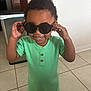 toddler, child, sunglasses, green_romper, smiling, indoor, kitchen, tile_floor, happy, short_hair, cute, playful, person, young_child, standing, black_sunglasses, home, casual_clothing, daylight, portrait