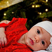 Amara joined the competition — help win amazing prizes! baby, background_bokeh, celebration, child, christmas_lights, closeup, cute, eyes, face, festive, flower_accessory, hand, headband, holiday, infant, lying_down, portrait, red_dress, soft_skin, warm_lighting