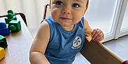 énoha a rejoint le concours — aidez-le/la à gagner de superbes lots ! toddler, child, blue_eyes, snack, wooden_table, building_blocks, indoor, natural_light, curious_expression, blue_shirt, striped_shorts, high_chair, frosted_window, hand, face, person, furniture, play, casual_clothing, daylight
