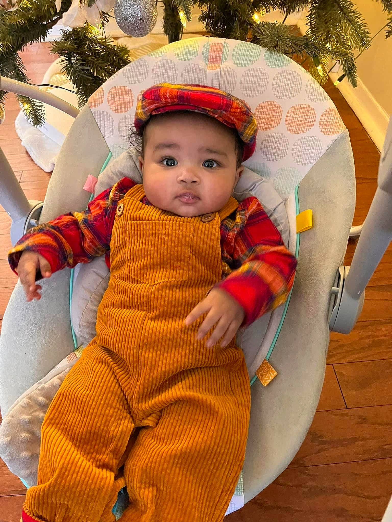 Noel is registered to the contest to win money with this photo: baby, baby_products, baby_toddler_clothing, child, christmas_ornament, costume_hat, facial_expression, fashion_accessory, fun, grass, happy, headwear, human_body, ornament, outerwear, pattern, person, sitting, skin, sleeve