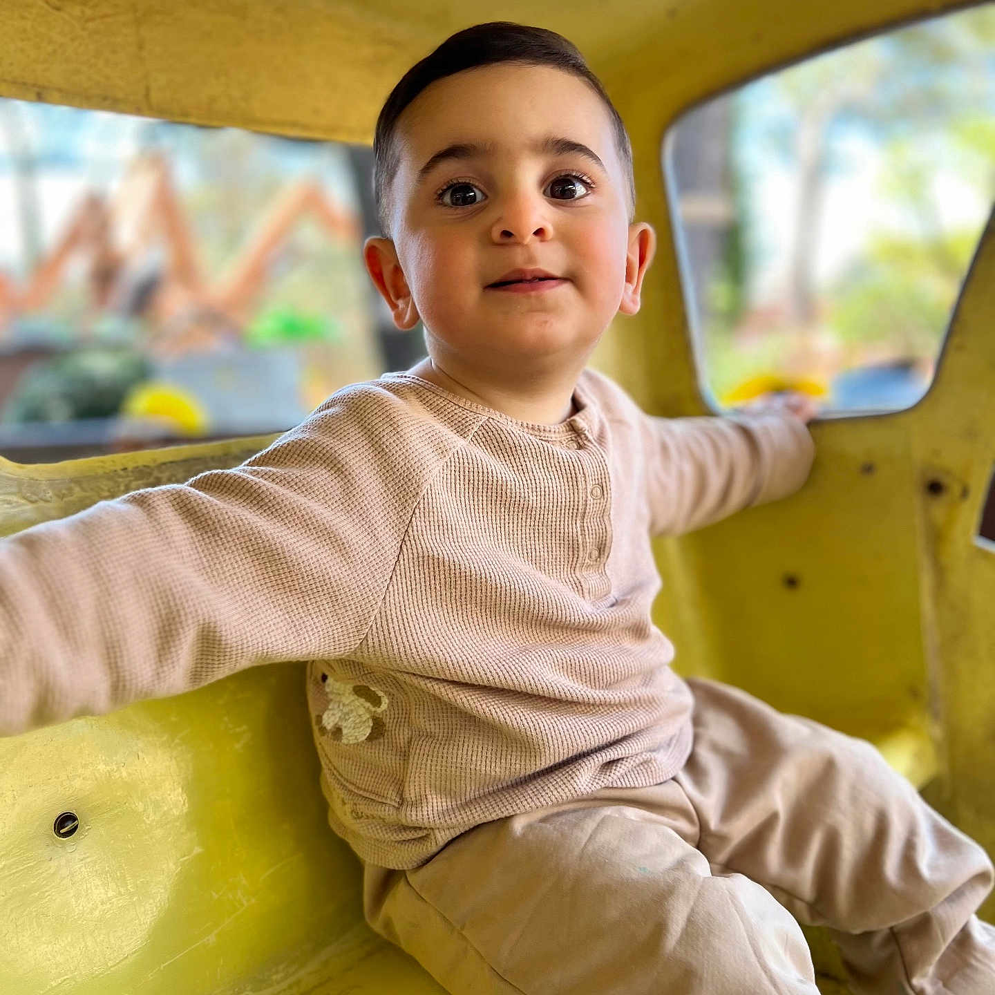 Mickael a rejoint le concours — aidez-le/la à gagner de superbes lots ! background_blur, boy, casual, child, clothing, curious, cute, eyes, face, hair, happy, indoor, long_sleeve, pants, playground, sitting, smile, toddler, window, yellow