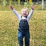 Carson is registered to the contest to win money with this photo: blonde_hair, child, daylight, denim_overalls, fence, field, grass, greenery, happy, nature, outdoor, person, playful, running, smiling, summer, sunflower, toddler, white_shirt, young_child