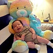 Zara joined the competition — help win amazing prizes! baby, infant, child, smiling, sitting, portrait, teddy_bear, plush_toy, rainbow_colors, chair, indoors, home, cozy, warm_lighting, striped_fabric, onesie, socks, happy, playful, ai_generated_content