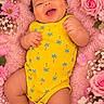 baby, infant, child, smiling, laughing, portrait, lying_down, pink_blanket, flowers, roses, daisies, floral_background, yellow_outfit, romper, curly_hair, hands, feet, indoor, closeup, happy
