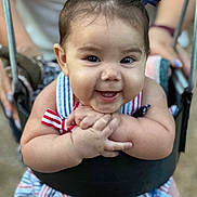 Isabella is registered to the contest to win money with this photo: baby, child, smiling, swing, bows, hair, hands, dress, striped, happy, outdoor, person, cute, infant, closeup, playground, joyful, young, seat, fun