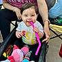 Isabella joined the competition — help win amazing prizes! baby, smiling, stroller, toy, pink_straw, tshirt, adult_hand, outdoor, child, happy, colorful, sitting, person, casual, playful, accessory, footwear, blanket, watch, nail_polish