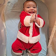 Zion joined the competition — help win amazing prizes! baby, infant, child, smiling, santa_outfit, red_clothing, fur_trim, bassinet, crib, mattress, happy, indoors, portrait, hands_clasped, socks, blanket, cozy, holiday, cute, joyful