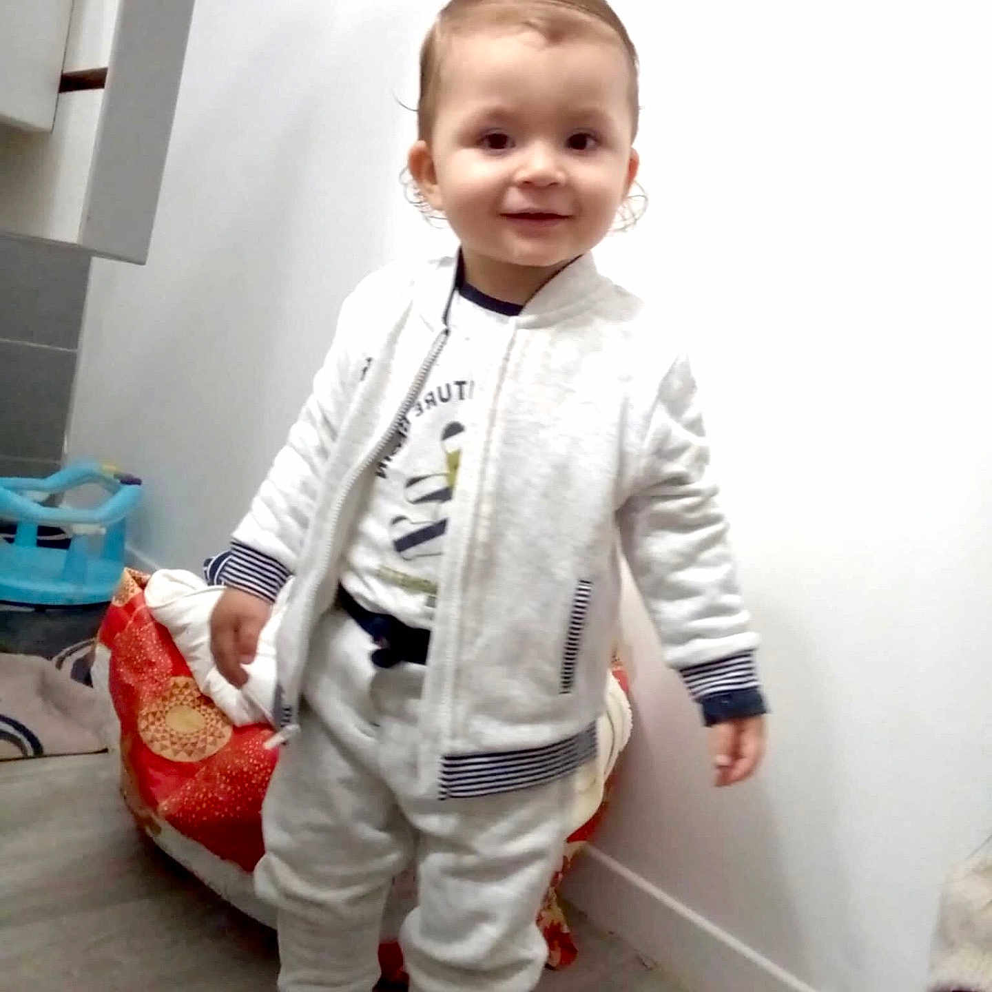 Ayden participe au concours pour gagner de l'argent avec cette photo : baby, ball, clothing, coat, face, football, footwear, head, indoors, jacket, pants, person, photography, portrait, shoe, sitting, soccer, soccerball, sport, standing