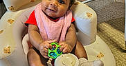 Taliyah joined the competition — help win amazing prizes! baby, infant, child, toy, pink_bib, red_clothing, socks, inflatable_seat, teddy_bear_pattern, indoor, carpet, floor, curly_hair, cute, smiling, playful, baby_seat, child_playing, colorful_quilt, baby_accessories