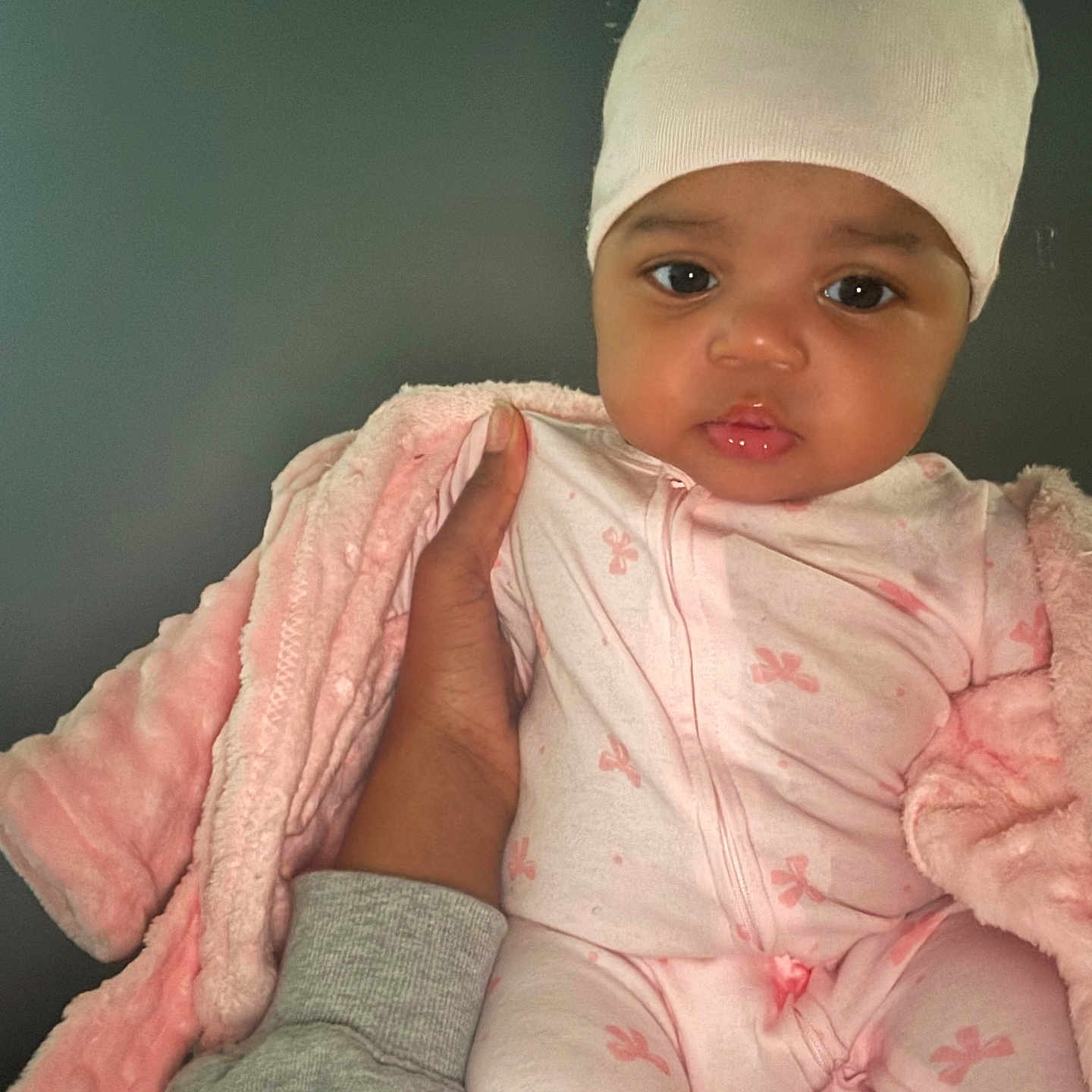 Chole joined the competition — help win amazing prizes! baby, infant, pink_onesie, hat, blanket, hand, adult_hand, soft_texture, indoor, portrait, cute, child, person, calm, warm, tender, face, eyes, clothing, newborn