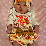 Kayelani is registered to the contest to win money with this photo: baby, infant, child, thanksgiving, headband, bow, clothing, blanket, heart_pattern, cute, lying_down, pink, white, orange, yellow, skirt, socks, portrait, indoors, festive