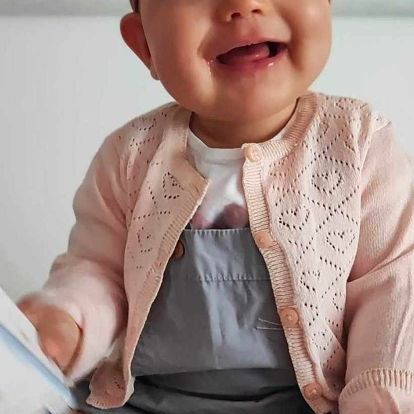 Brooke participe au concours pour gagner de l'argent avec cette photo : baby, bare_feet, book, child, cozy, cute, face, grey_dress, hands, happy, headband, home, indoor, infant, pink_cardigan, portrait, sitting, smiling, soft_blanket, toddler