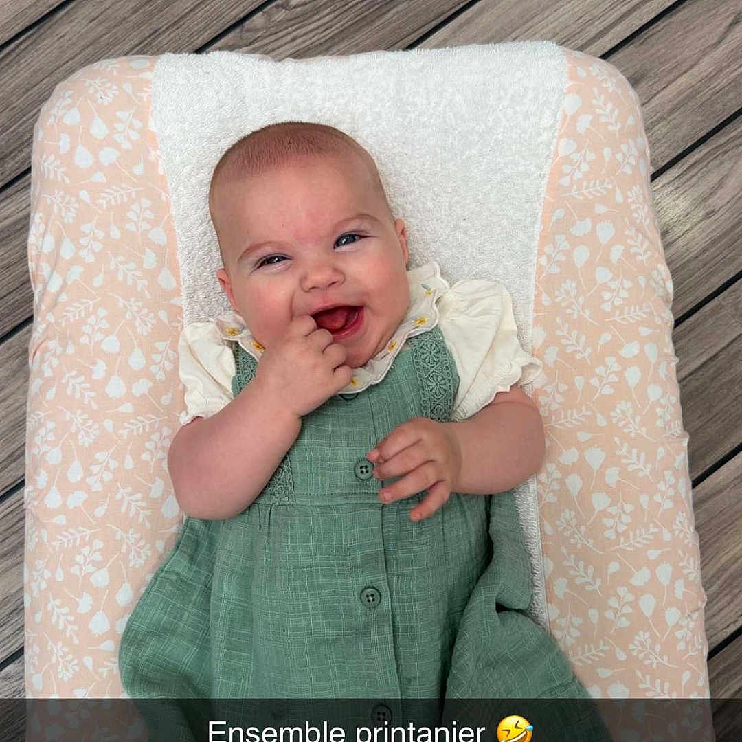Rose a rejoint le concours — aidez-le/la à gagner de superbes lots ! baby, child, smiling, green_dress, tights, cushion, wooden_floor, face, happy, portrait, infant, sitting, clothing, pattern, flooring, cute, person, baby_bedding, indoors, funny