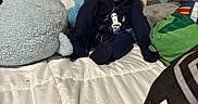 Kaleb joined the competition — help win amazing prizes! baby, plush_toys, bed, white_bedspread, blue_clothing, stuffed_shark, stuffed_bear, green_wall, child, smiling, sitting, cute, indoor, soft_toys, toddler, face, head, person, cozy, playful