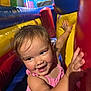 Maliyah is registered to the contest to win money with this photo: toddler, child, playground, inflatable, colorful, pink_clothing, happy, smiling, indoor, fun, hands, face, young_child, activity, play, bright_colors, excited, cheerful, casual_clothing, closeup