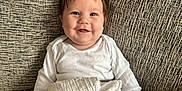 Tayler is registered to the contest to win money with this photo: baby, smile, toy, giraffe_toy, blanket, couch, child, happy, indoor, infant, clothing, face, person, sitting, cute, young_child, soft_toy, playful, comfort, bright_eyes