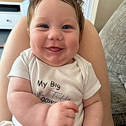 Tayler joined the competition — help win amazing prizes! baby, smile, infant, cute, happy, chubby, face, person, clothing, sitting, indoor, home, couch, arm, legs, shirt, tongue, skin, head, portrait