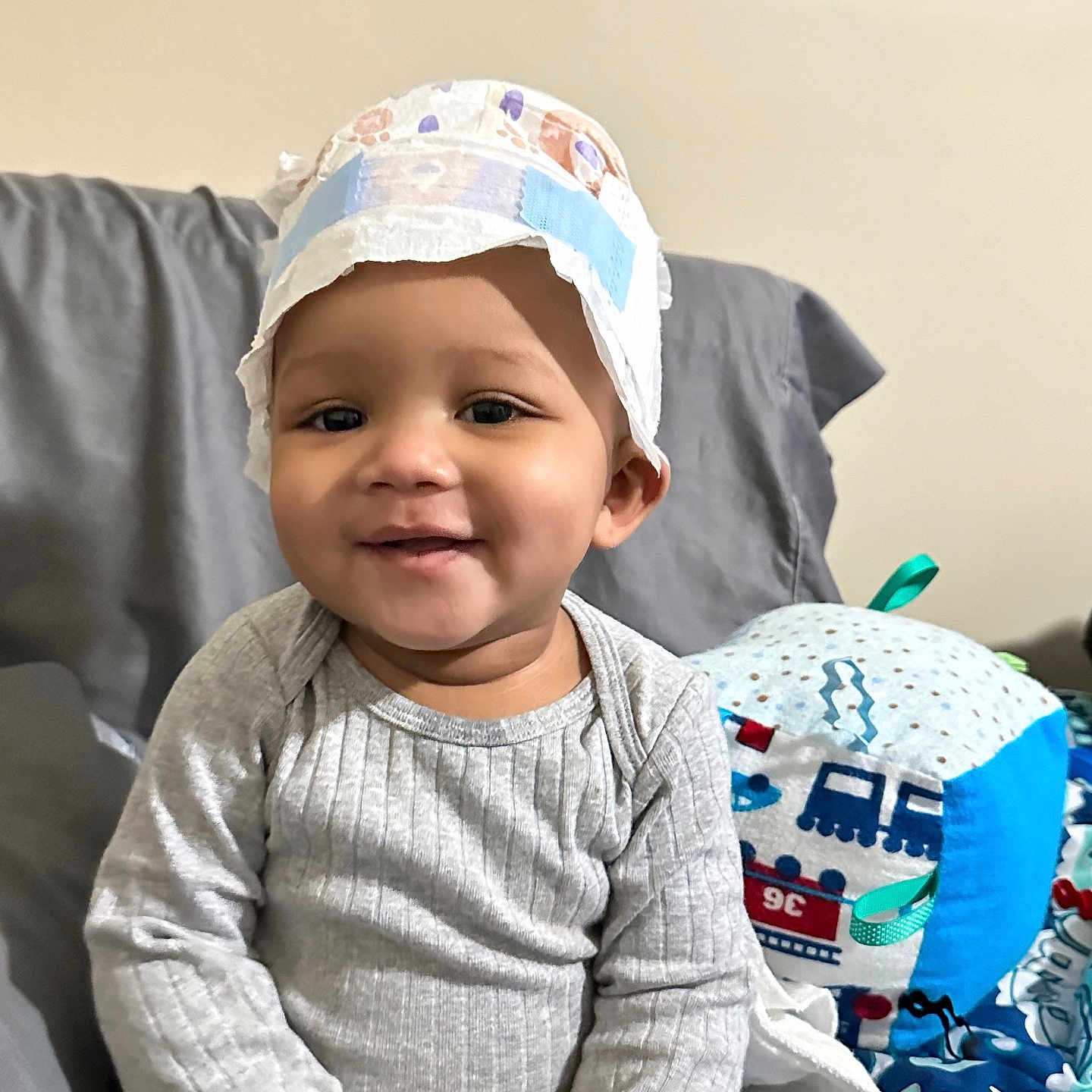 Malakai is registered to the contest to win money with this photo: baby, babylaughing, baseballcap, cap, clothing, couch, cushion, face, furniture, happy, hat, head, homedecor, pants, person, photography, portrait, sitting, sleeve, smile